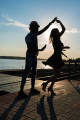 man and woman dancing salsa at sunset