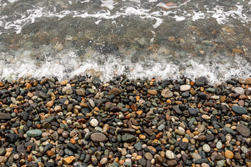 waves of the blue sea on a pebble beach. small pebble stones by the sea.