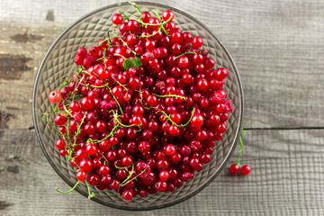 top view glass vintage bowl full of red ripe currant berries on a wooden table