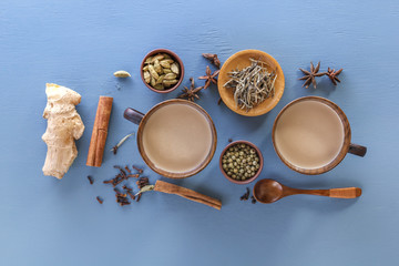 Traditional Indian tea masala with milk and spices on a blue background. Top view. Copy space