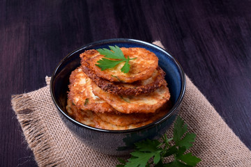 Vegetable pancakes topped with parsley leaves on a dark plate