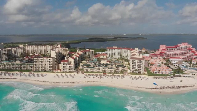 Flying over resort looking down at pool and bar area. From beach to resort, bird's eye view of tropical resort destination in Cancoon, Mexico. Drone shot over ocean and all inclusive hotel destination