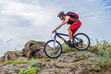 Fototapeta na wymiar Concept of extreme cycling, a biker on a mountain bike on the blue sky background, free space.