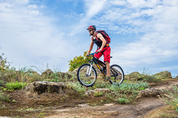 Fototapeta na wymiar Cyclist on a mountain bike riding on the rock, free space for your text.