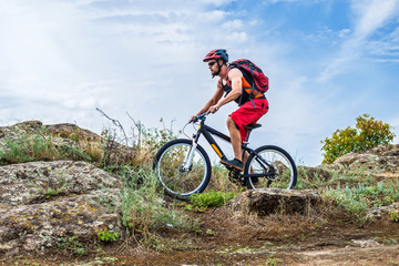 Naklejka na ściany i meble Cyclist riding down the rock on a mountain bike, extreme enduro cycling.