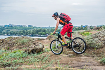 Cyclist descending down the rock on a mountain bike, an active lifestyle.