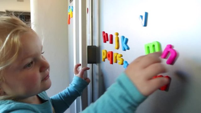 Toddler playing with colorful fridge magnets