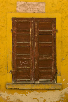 Fassade mit braunem Fensterladen aus Holz eines alten Hauses, Facade with brown wooden shutter of an old house