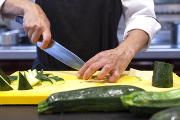 Manos de cocinera cortando calabacín