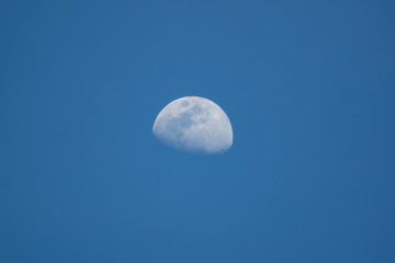 Half moon on blue sky background on daytime