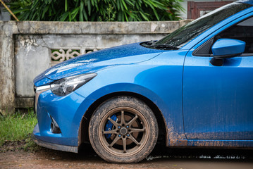 Blue car Dirty car on dirt road after rain