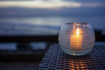 candle on a table with beach view at sunset