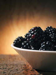 forest blackberries in a plate on a wooden background