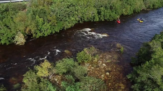 Aerial footage of white water kayaks paddling in the white water rapids on a freestone stream in the western cape of south africa during a winter storm.