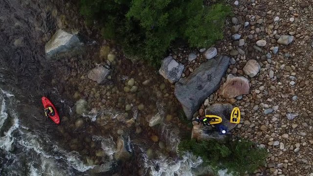 Aerial footage of white water kayaks paddling in the white water rapids on a freestone stream in the western cape of south africa during a winter storm.