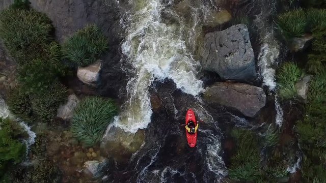 Aerial footage of white water kayaks paddling in the white water rapids on a freestone stream in the western cape of south africa during a winter storm.