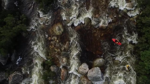 Aerial footage of white water kayaks paddling in the white water rapids on a freestone stream in the western cape of south africa during a winter storm.
