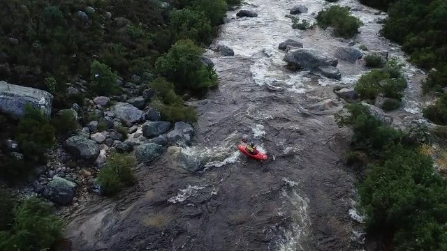 Aerial footage of white water kayaks paddling in the white water rapids on a freestone stream in the western cape of south africa during a winter storm.