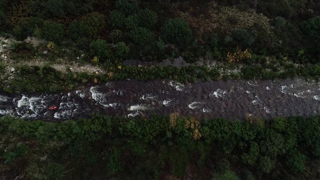 Aerial footage of white water kayaks paddling in the white water rapids on a freestone stream in the western cape of south africa during a winter storm.