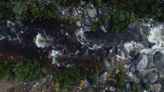 Aerial footage of white water kayaks paddling in the white water rapids on a freestone stream in the western cape of south africa during a winter storm.