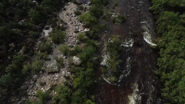 Aerial footage of white water kayaks paddling in the white water rapids on a freestone stream in the western cape of south africa during a winter storm.