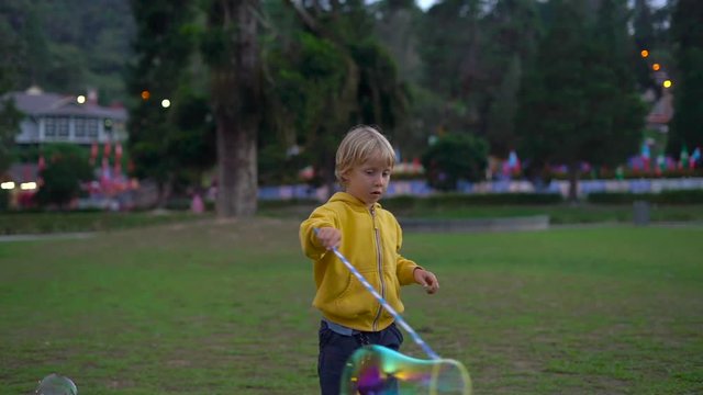 Slowmotion shot of a little boy making a big soap bubles in a park
