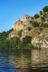 Naklejka premium Ancient hermitage at the foot of a cliff that ends in the river.