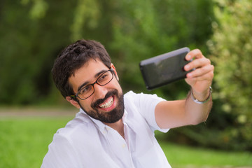 Fototapeta premium Happy Young man taking a selfie in the park