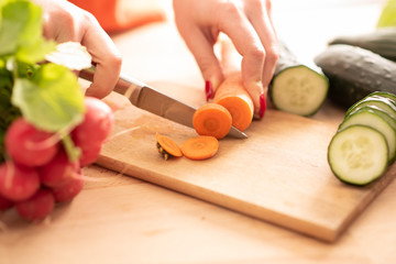 Obraz na płótnie Canvas woman hands cutting fresh veg with knife on cutting board