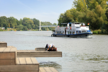 Młoda dziewczyna wypoczywa czytając książkę nad rzeką Odrą we Wrocławiu.