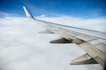 airplane wing against clouds and blue sky background