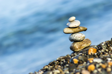 Fototapeta na wymiar Pyramid of pebbles on the beach.Waves in background.