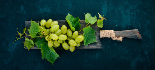 Green grapes with leaves of grapes on a stone table. Top view. Free space for text.