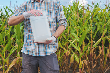 Farmer holding pesticide chemical jug in cornfield