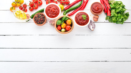 Preparation of tomato sauces and seasonings. Cherry tomatoes, spices, chili peppers. Top view. On a white wooden background. Free copy space.