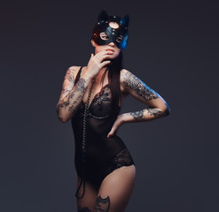 Fototapeta na wymiar Sexy woman wearing black lingerie in BDSM cat leather mask and accessories posing on dark background. 