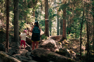 Hiking in the woods. Mother and daughter are walking on a path in a warm sunny forest. Impassable rocky trail. Skule mountain close to Docksta in northern Sweden.