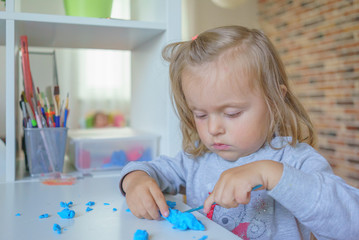 Baby girl toddler playing and learning with plasticine, close-up shot