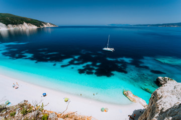 Azure water of Fteri beach, Cephalonia Kefalonia, Greece. White catamaran yacht in clear blue sea...