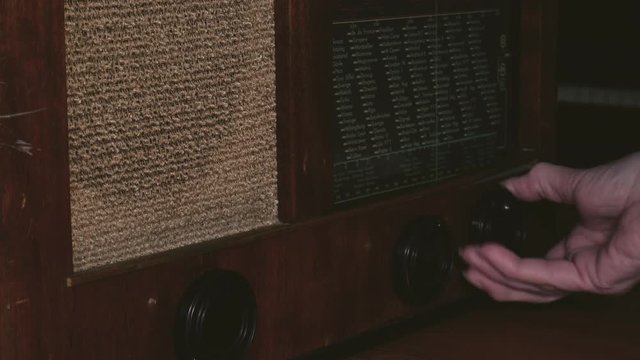 An old woman sets up a radio channel on an old radio