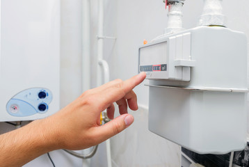 Person reading the natural gas meter in the boiler room of private house, counter for distribution domestic gas. Selective focus.