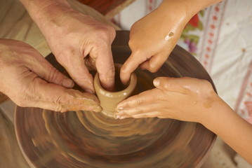 Man and children hands molding a clay in pottery workshop