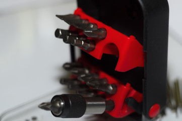 Bits holder in box and many tool bits on white background. Close-up view. Red element in plastic...