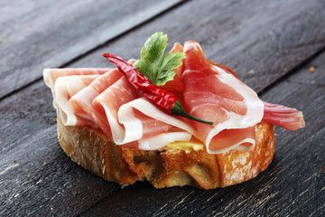 Sandwich with prosciutto or salami or crudo. Antipasti gourmet bruschetta snack.