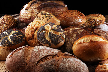 Different kinds of bread and bread rolls on board from above. Kitchen or bakery