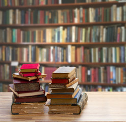 Stacks of old books with open one on wooden shelf in library