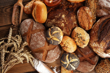 Different kinds of bread and bread rolls on board from above. Kitchen or bakery