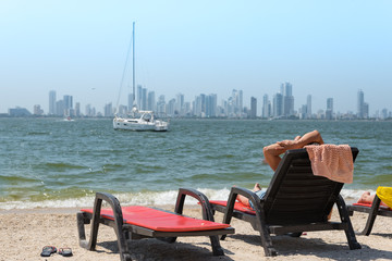 resting on the beach on the other shore of the Bay of Cartagena with modern city in the background. Colombia
