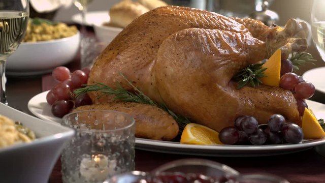 Thanksgiving turkey dinner with gravy, dinner rolls, stuffing or dressing, green bean casserole, cranberry sauce, and wine.