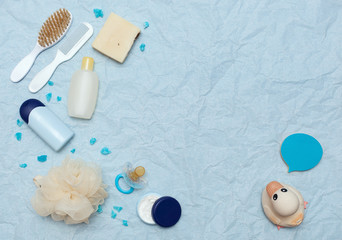Fototapeta na wymiar Bath products flat lay. Baby bathing, Free space for text. The top view of a rubber duck, a bottle of shampoo, body oil, cream, a comb and a loofah, dummy 